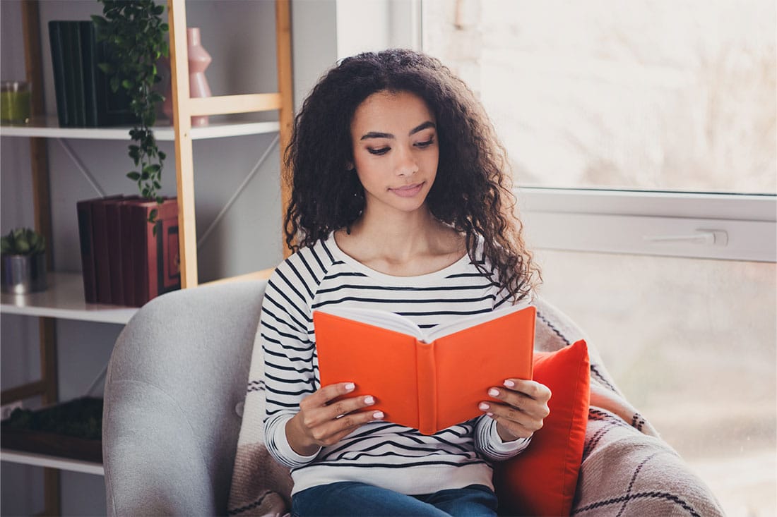 Woman sitting in armchair reading a book