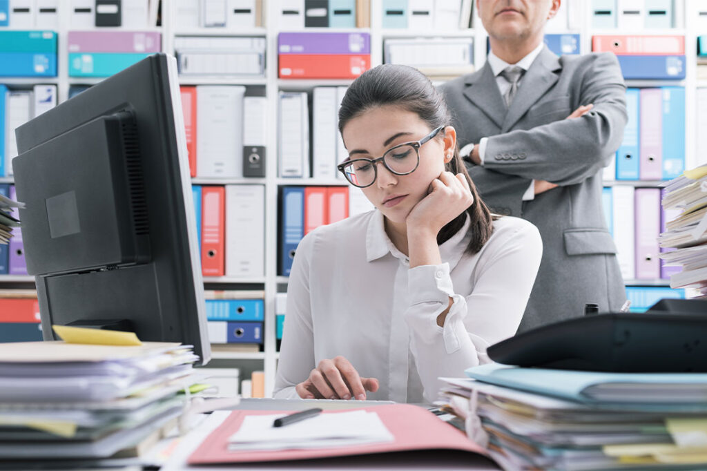 Boss watching over his employee and standing behind her