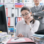 Boss watching over his employee and standing behind her